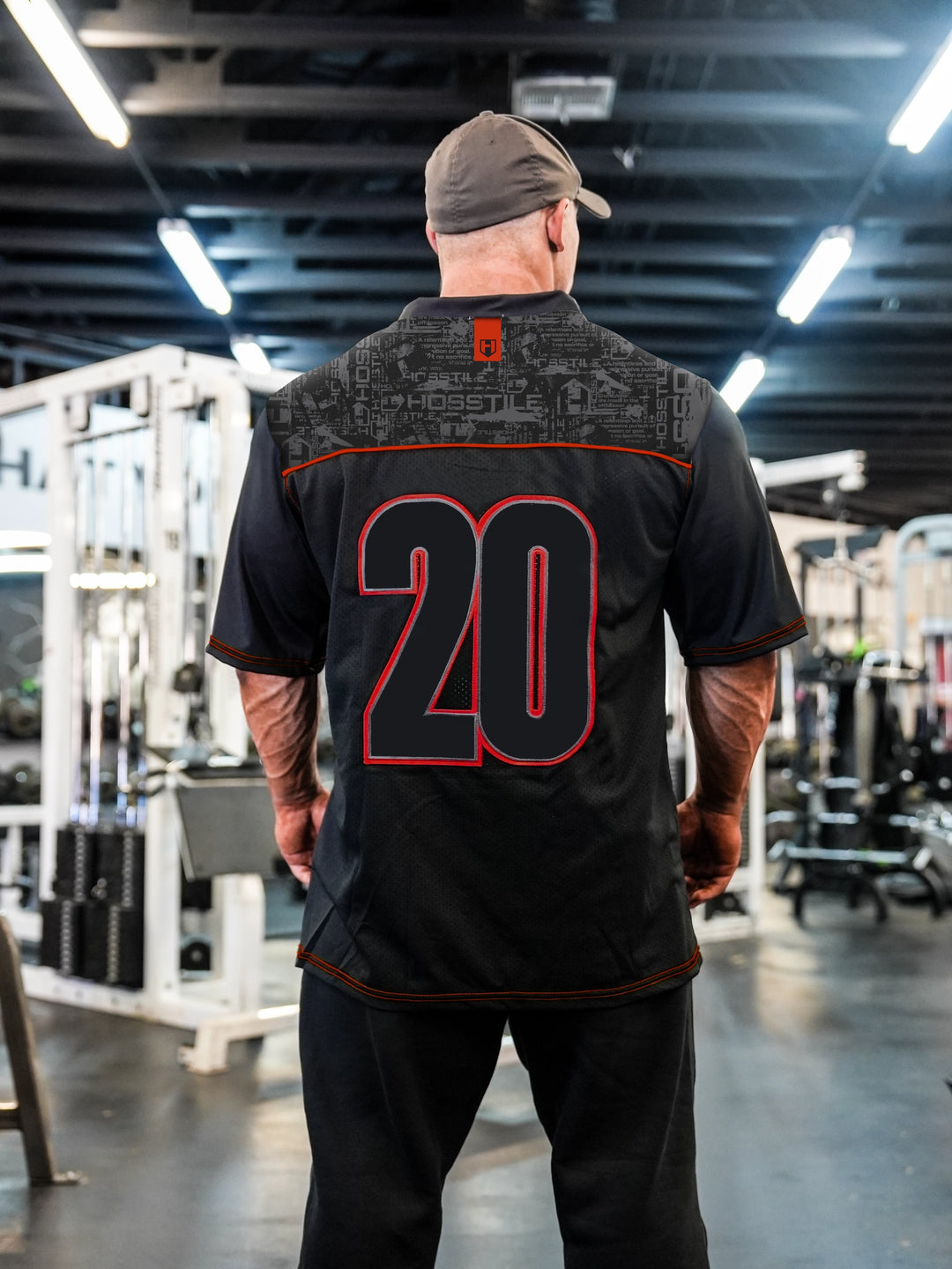 Bodybuilder Martin Fitzwater wearing the Hosstile Olympia Jersey in the Gym#color_black-red